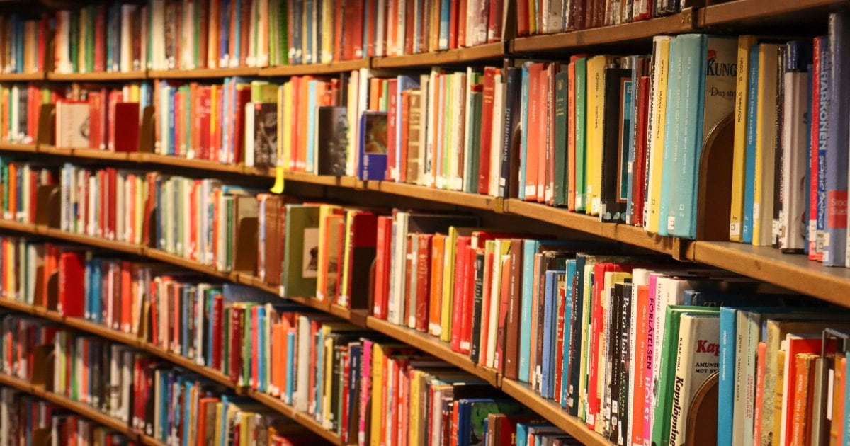 A shelving area of a library that has six shelves and is full of books