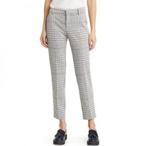 A woman wearing a white top, gray plaid pants, and black loafers