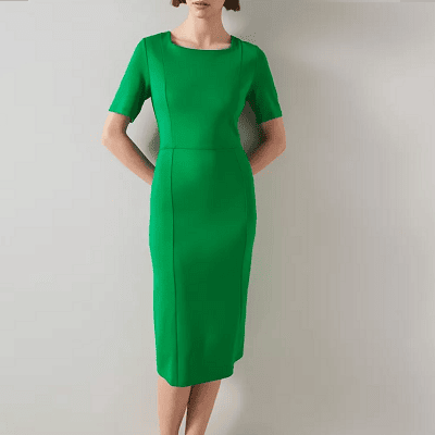 A woman wearing a green sheath dress with pink heels