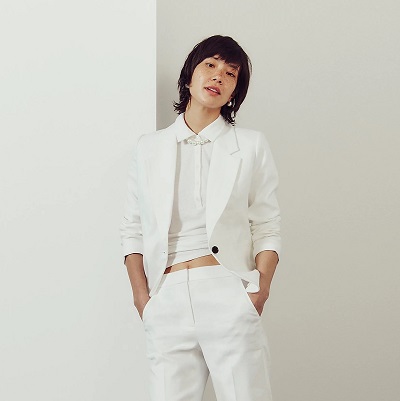 A woman wearing a white top and white suit