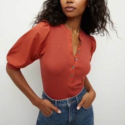 A woman wearing a peach puff sleeve top and a denim pants