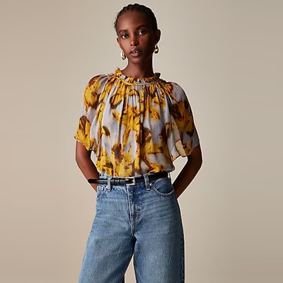 A woman wearing a yellow-print blouse, blue jeans, and a black belt