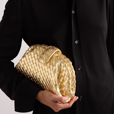 woman holds gold leather clutch with braided leather detail