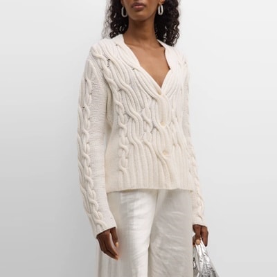 A woman wearing an ivory cable sweater and white pants