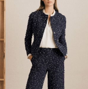 woman wears collarless jacket and matching pants in a textured, nubby fabric; both are navy with speckles of white