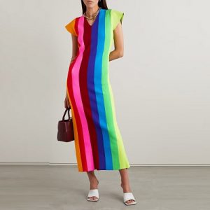 A woman wearing a rainbow vertical-stripe midi dress and holding a brown handbag