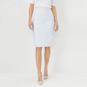 A woman wearing a white top, light blue pencil skirt, and nude heels