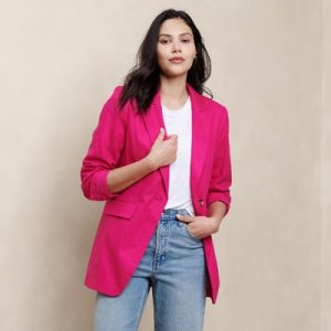A woman wearing a bright pink blazer, white top, and light blue jeans