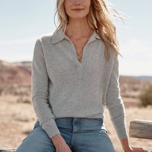 A woman wearing a gray polo sweater and denim pants