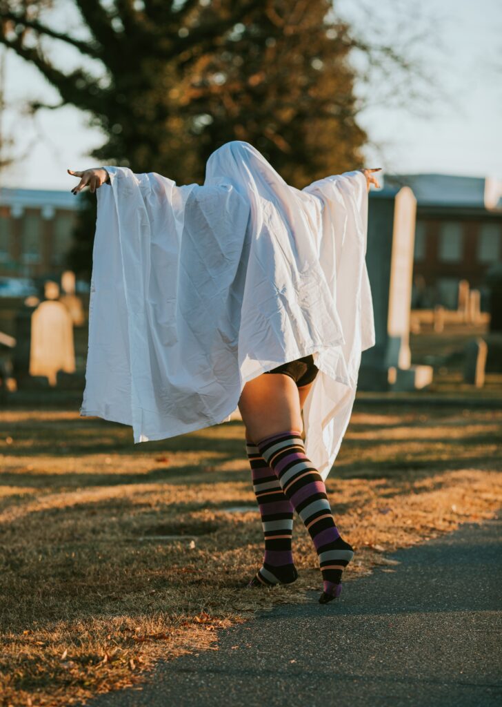 plus size woman with ghost costume, tights, and sneakers