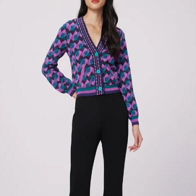 A woman wearing a printed purple cardigan and black pants