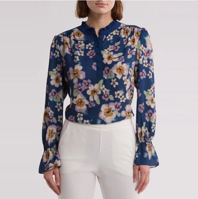 A woman wearing a blue floral top and white pants