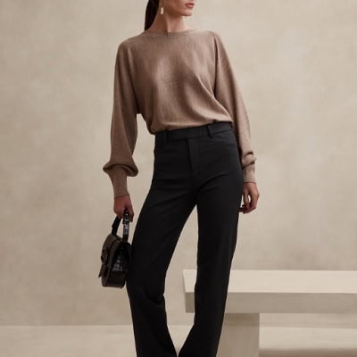 A woman wearing a brown long-sleeve blouse and black pants with black bag