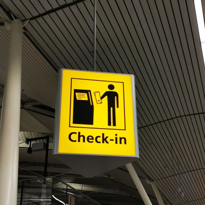 yellow sign reads "Check-in" and has icons of a person with a ticket standing next to a rectangular thing that is probably a ticket taking machine