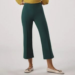 A woman wearing mustard long sleeve top and dark green cropped flare pants and cream shoes