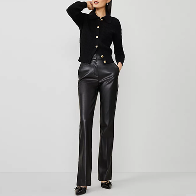 professional young woman wears black leather pants and a black cardigan with gold buttons; she