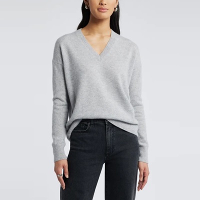 A woman wearing a light gray cashmere sweater and black jeans