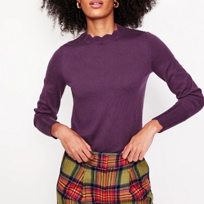 A woman wearing purple longsleeve sweater and red light green plaid pants