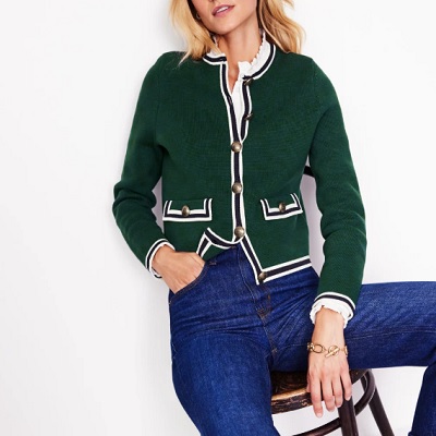 A woman wearing a green with white trim knit jacket and denim pants